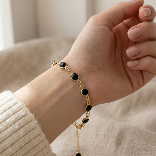 Armband goudkleurig met zwart steentje
